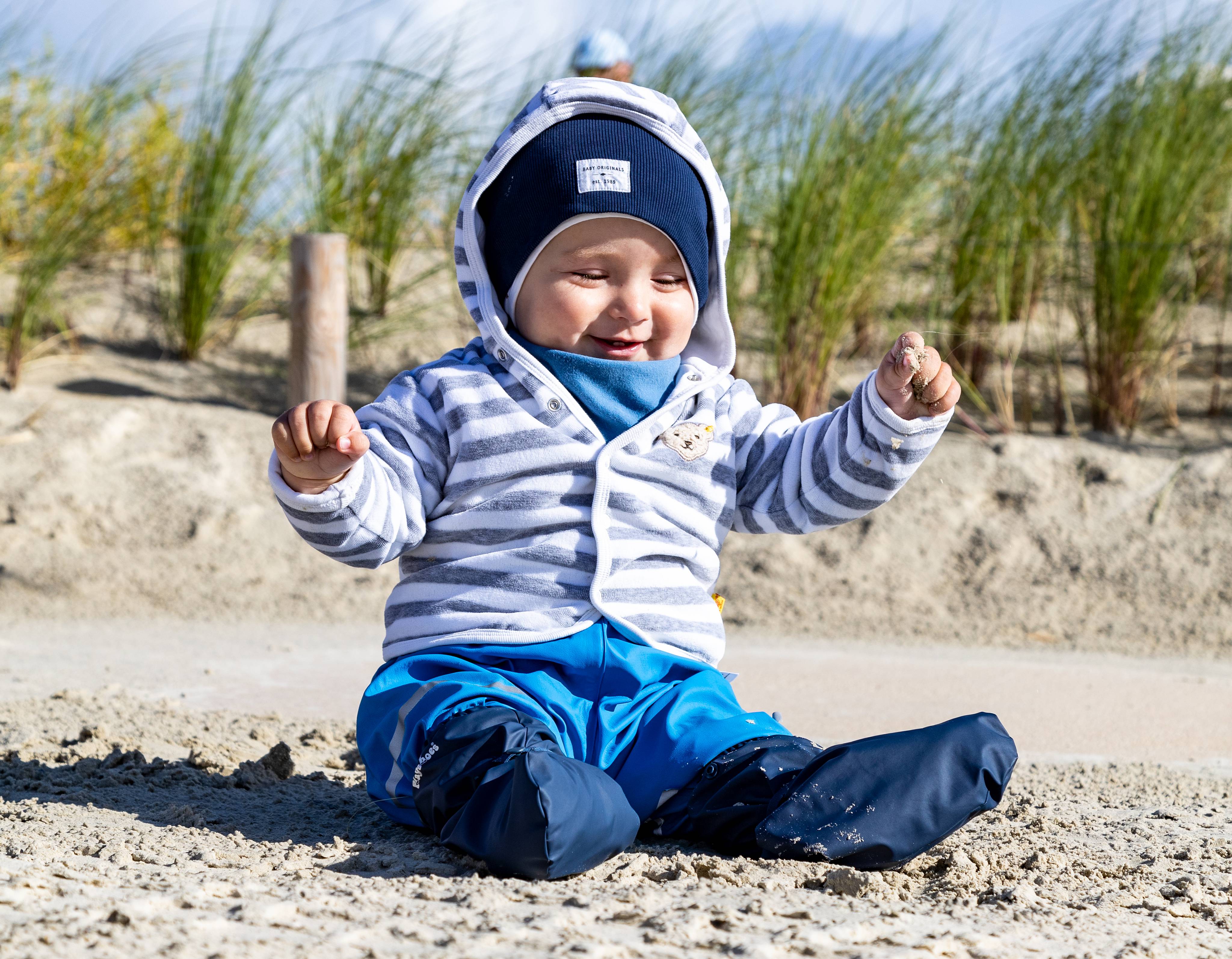 Kleines Kind sitzt am Strand der Nordsee
