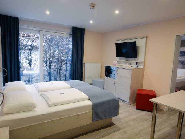 Hotelzimmer mit Doppelbett und Fernseher im Hotel Deichkrone