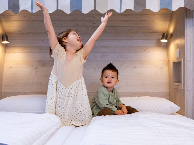 Zwei Kinder spielen im Bett im Hotel Deichkrone