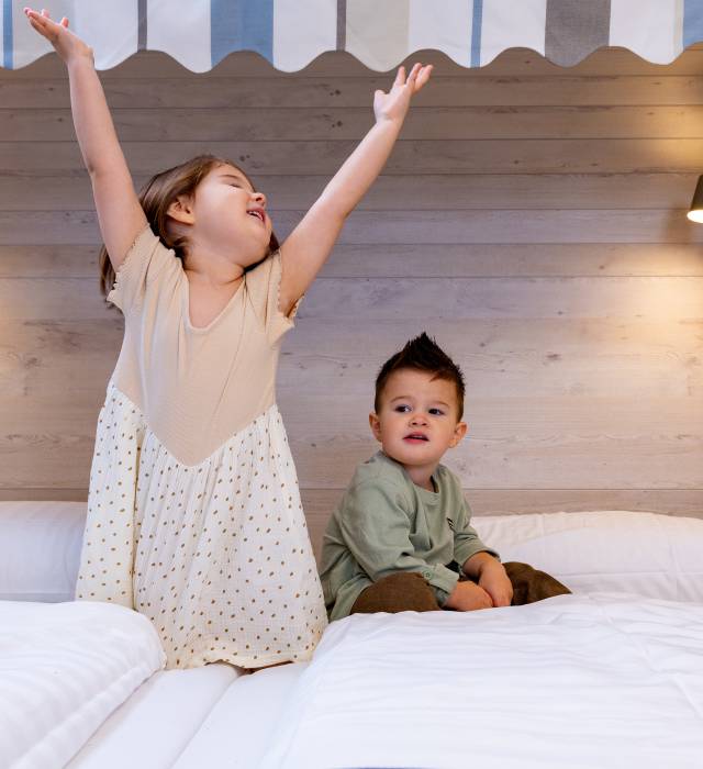 Zwei Kinder spielen im Bett im Hotel Deichkrone