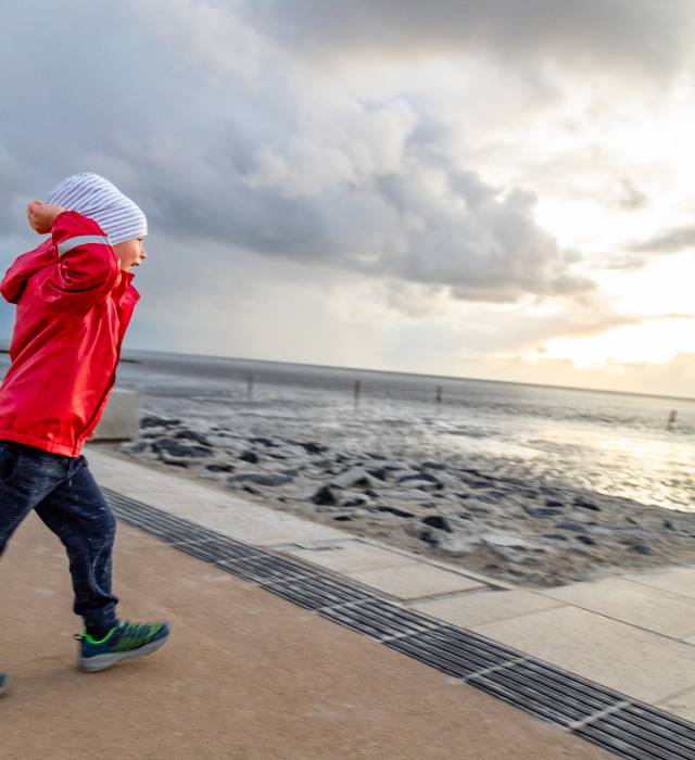 Ein Junge steht an der Strandpromenade der Nordsee