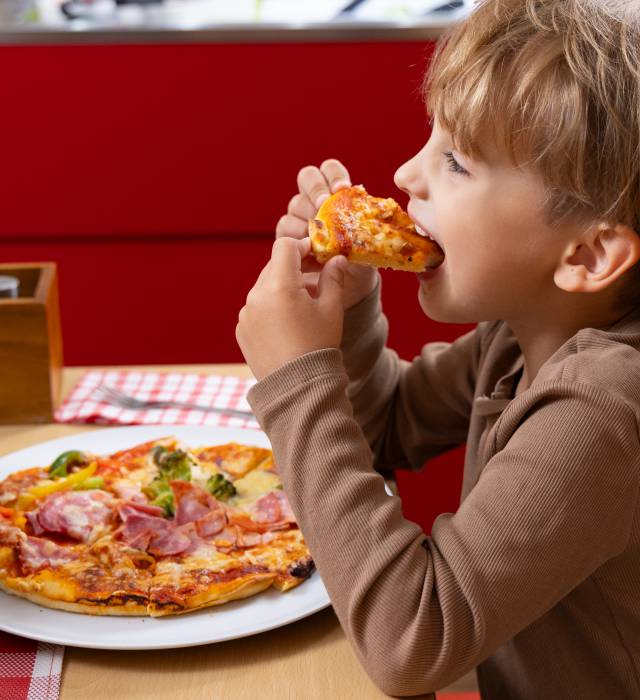 Junge ist Pizza im Restaurant des Hotel Deichkrone