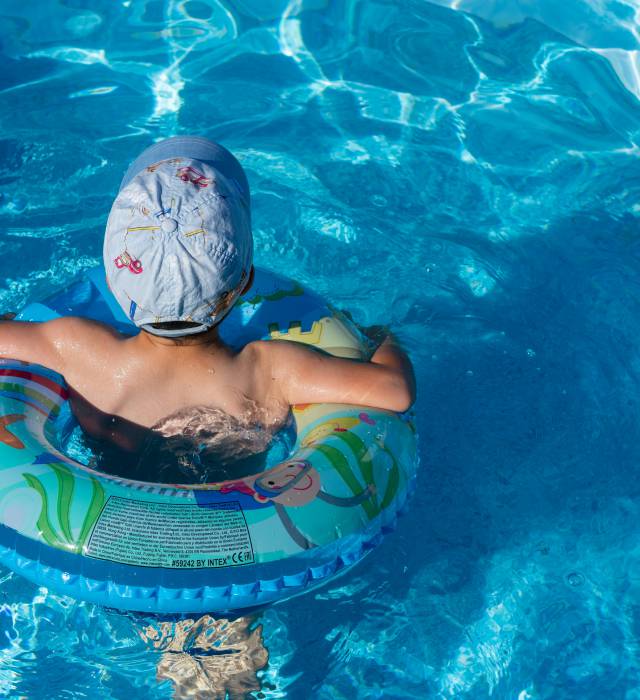 Junge mit Mütze und Schwimmring im Swimmingpool