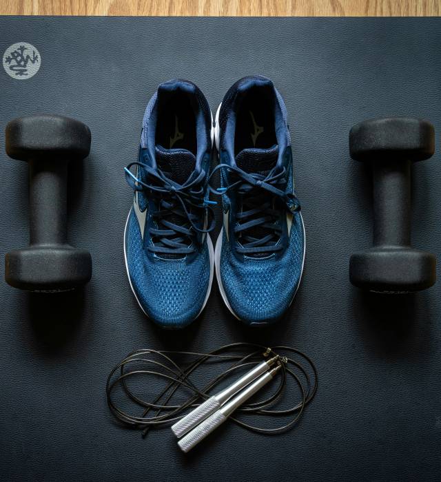 Hanteln, Springseil und Sportschuhe auf einer Matte