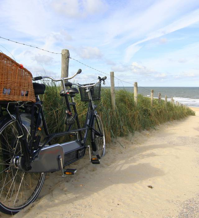 Tandem-Rad steht an einem Zaun und ein Weg führt zum Strand an der Nordsee