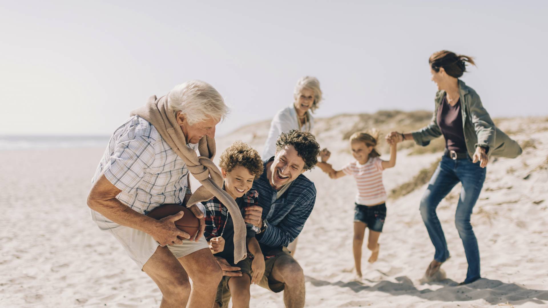Familie mit Oma und Opa spielen am Strand der Nordsee