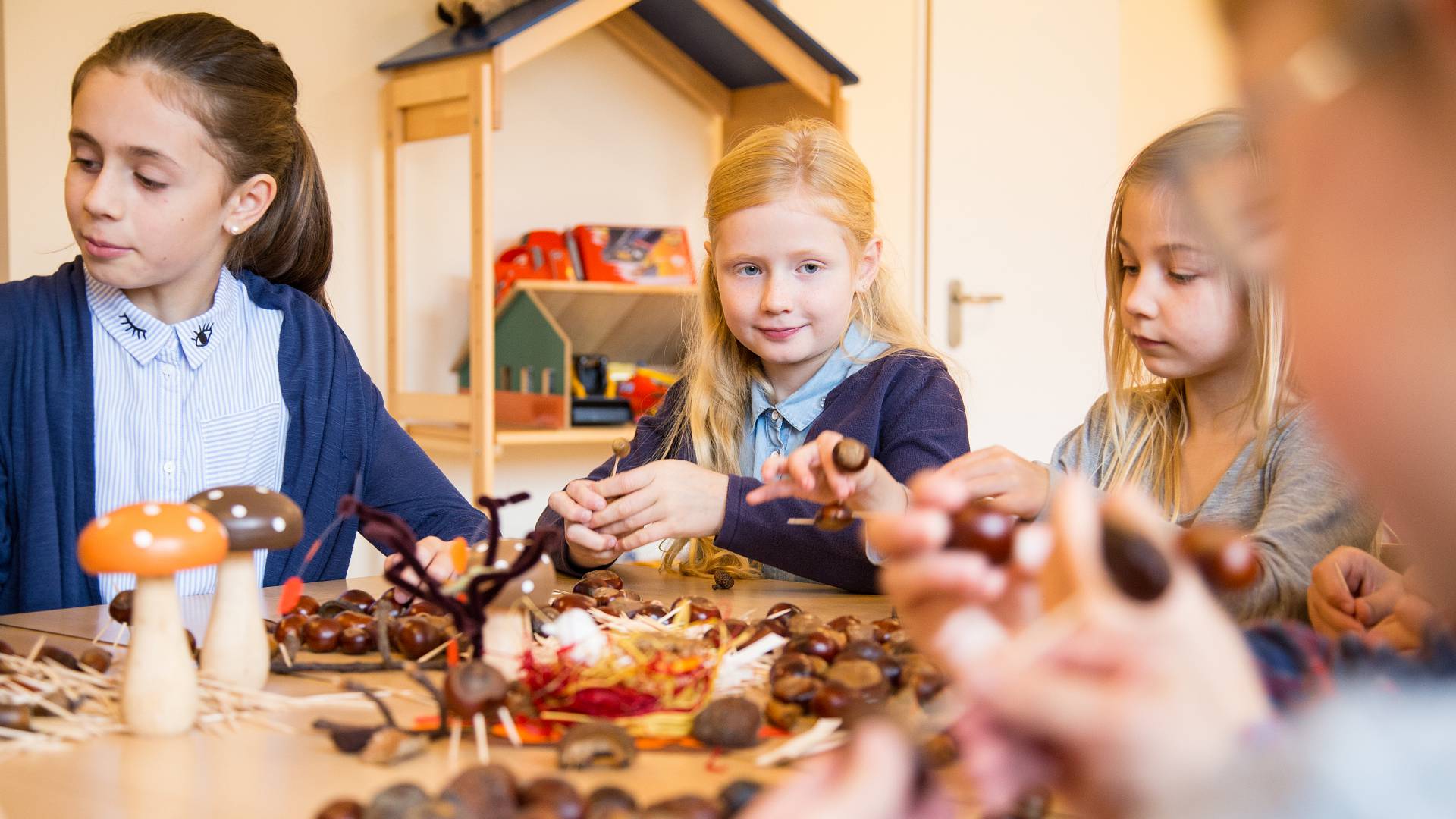 Mädchen sitzen am Tisch und basteln Herbstdeko