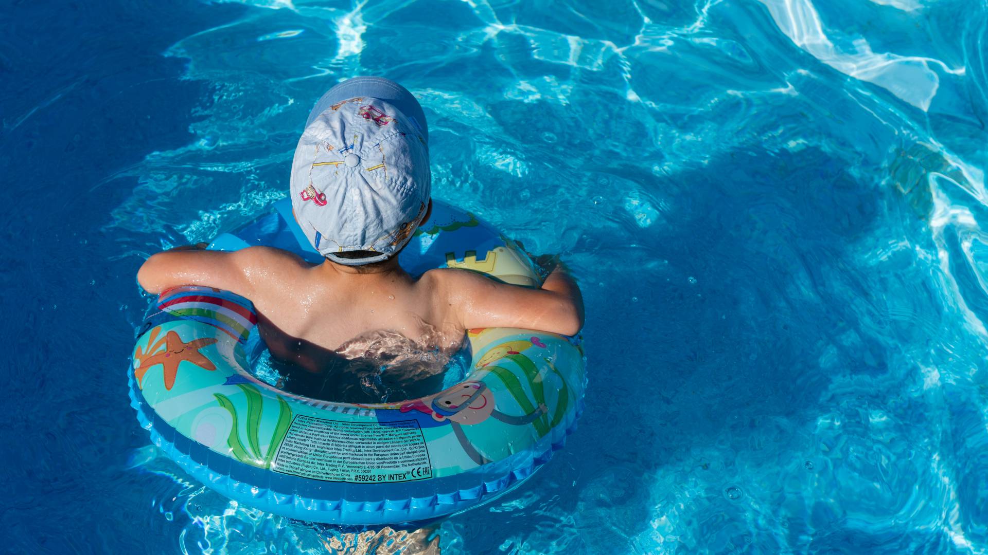 Junge mit Mütze und Schwimmring im Swimmingpool